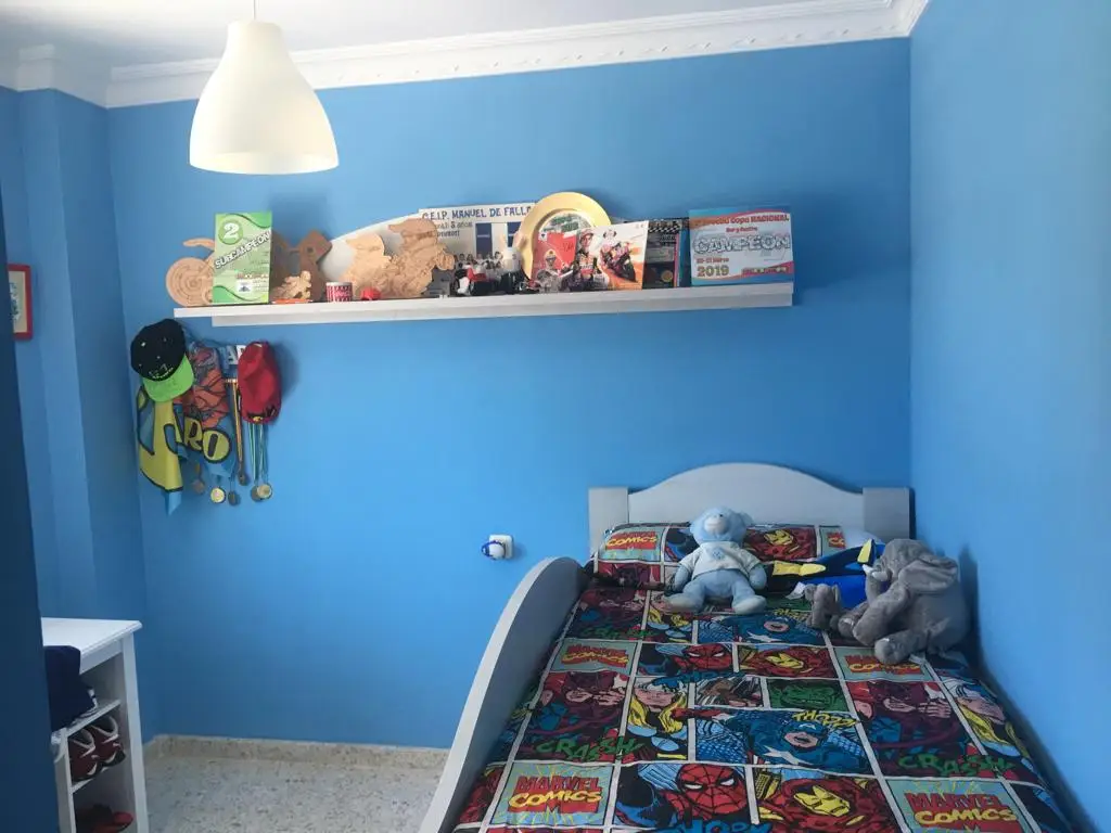 Trabajo de pintura en dormitorio infantil con paredes azul intenso y molduras blancas en Alicante