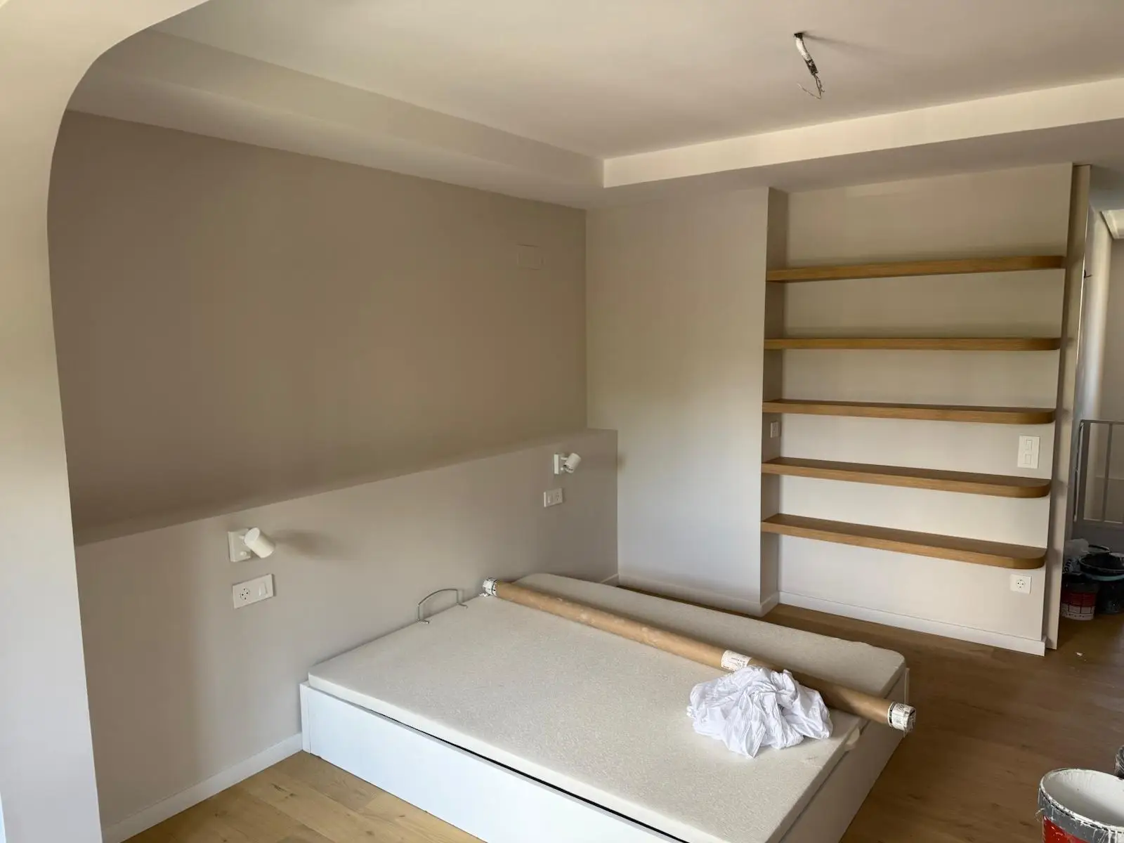 Servicio de pintura en dormitorio con paredes beige, estantería de madera integrada y suelo laminado en Alicante